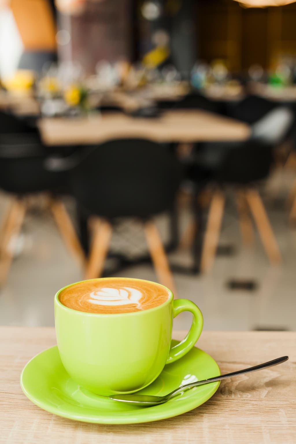 A green decorated coffee cup sits in a table nearby a bed and breakfast shared eating area