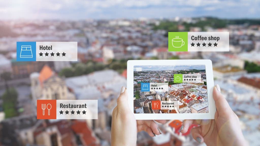 A person looks at a city from an augment reality screen showing hotels, restaurants and coffee shops