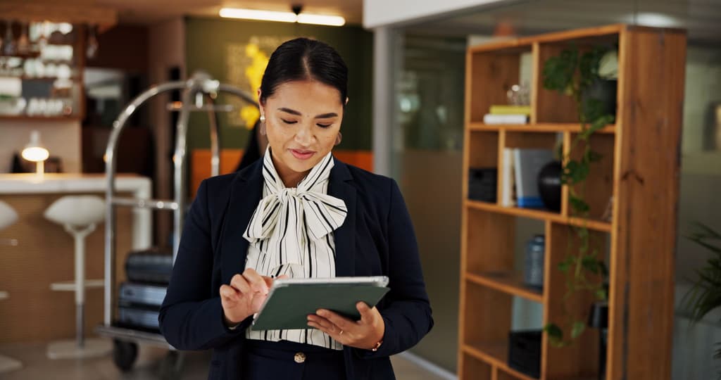 A general manager checks her property management system at a hotel lobby