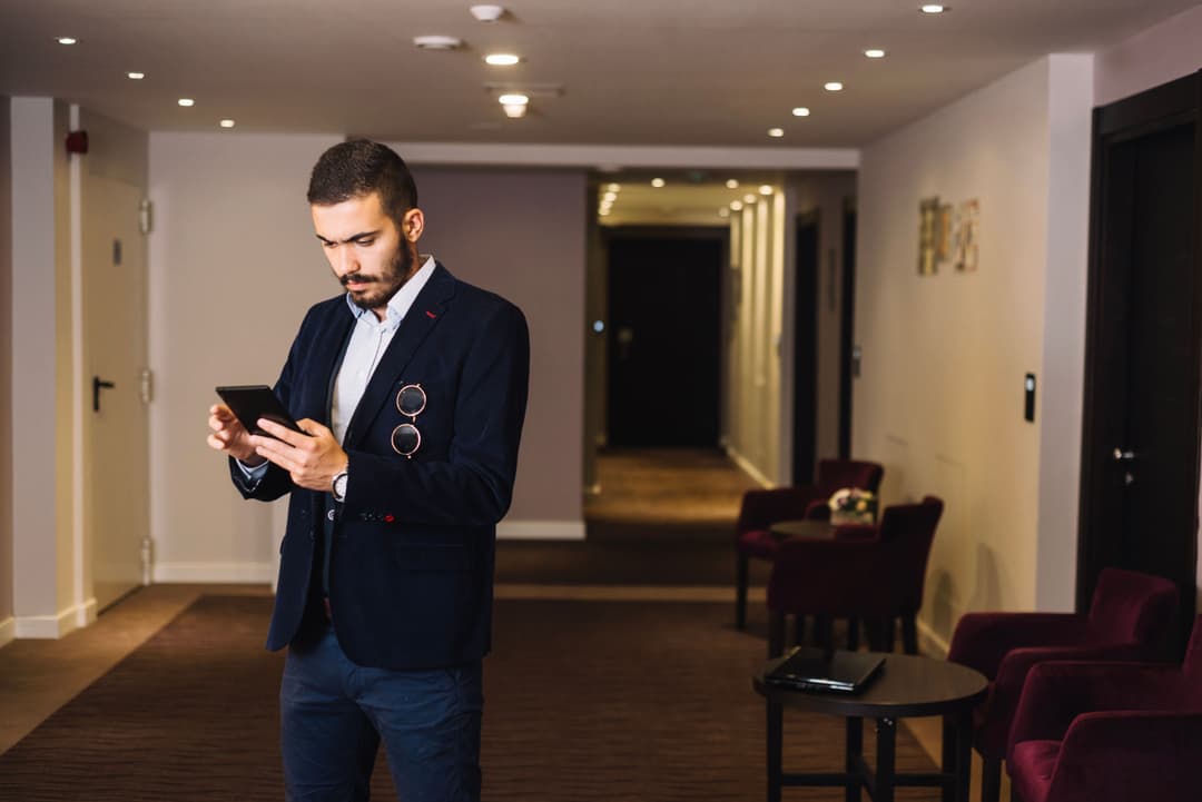 A guest check his phone while waiting in a hotel room floor elevator area