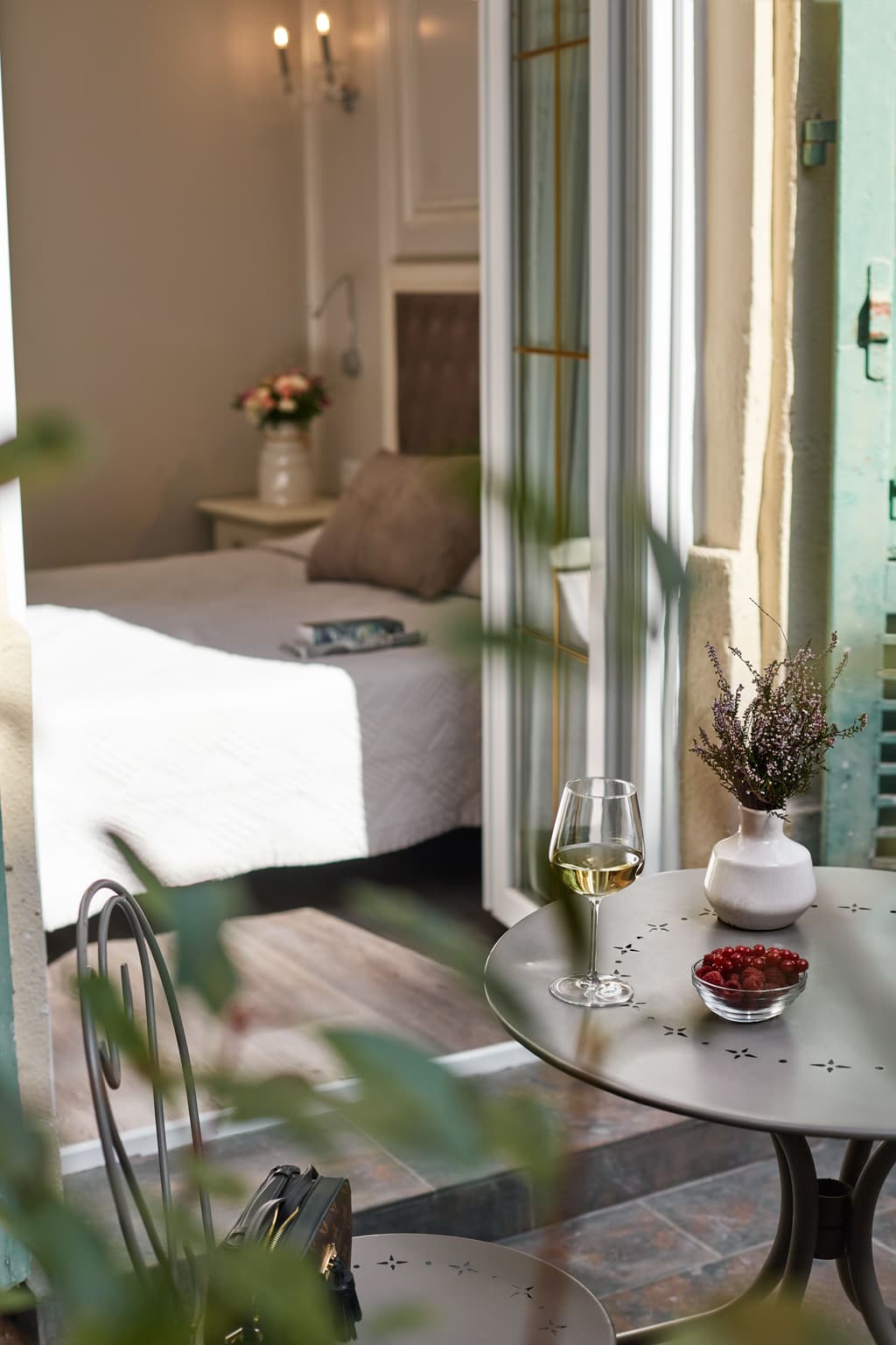A boutique hotel room opening up to a balcony with drinks on a table