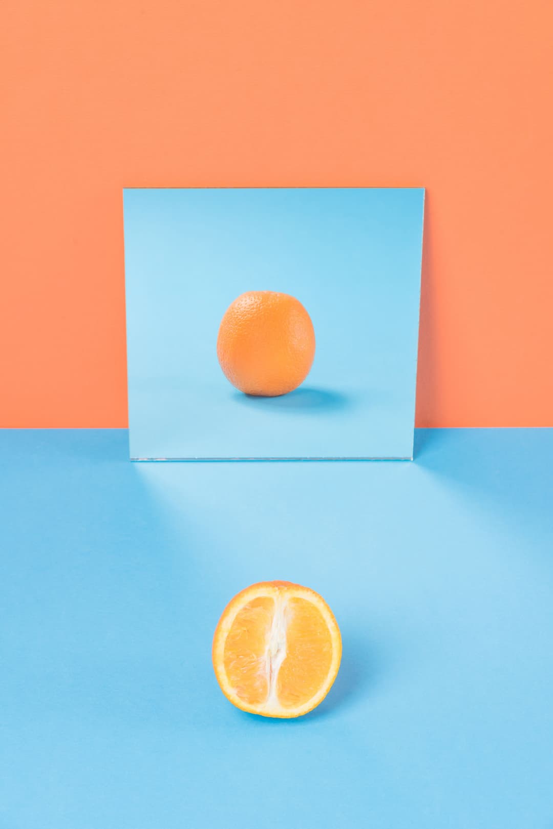 An orange is reflected in a mirror as full when in reality it is just half orange