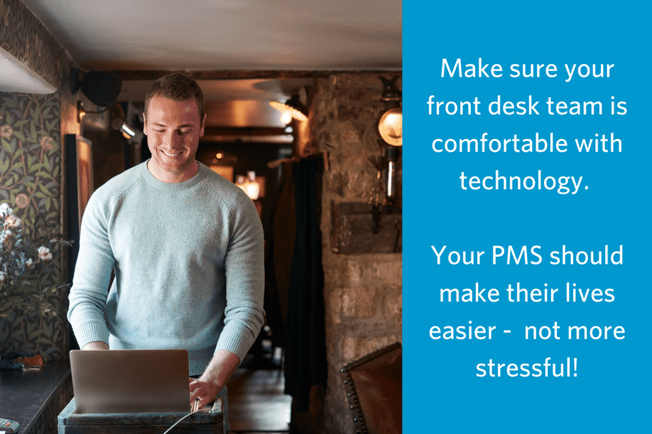 man standing at a desk using a laptop with text reading Make sure your front desk team is comfortable with technology. Your PMS should make their lives easier - not more stressful!